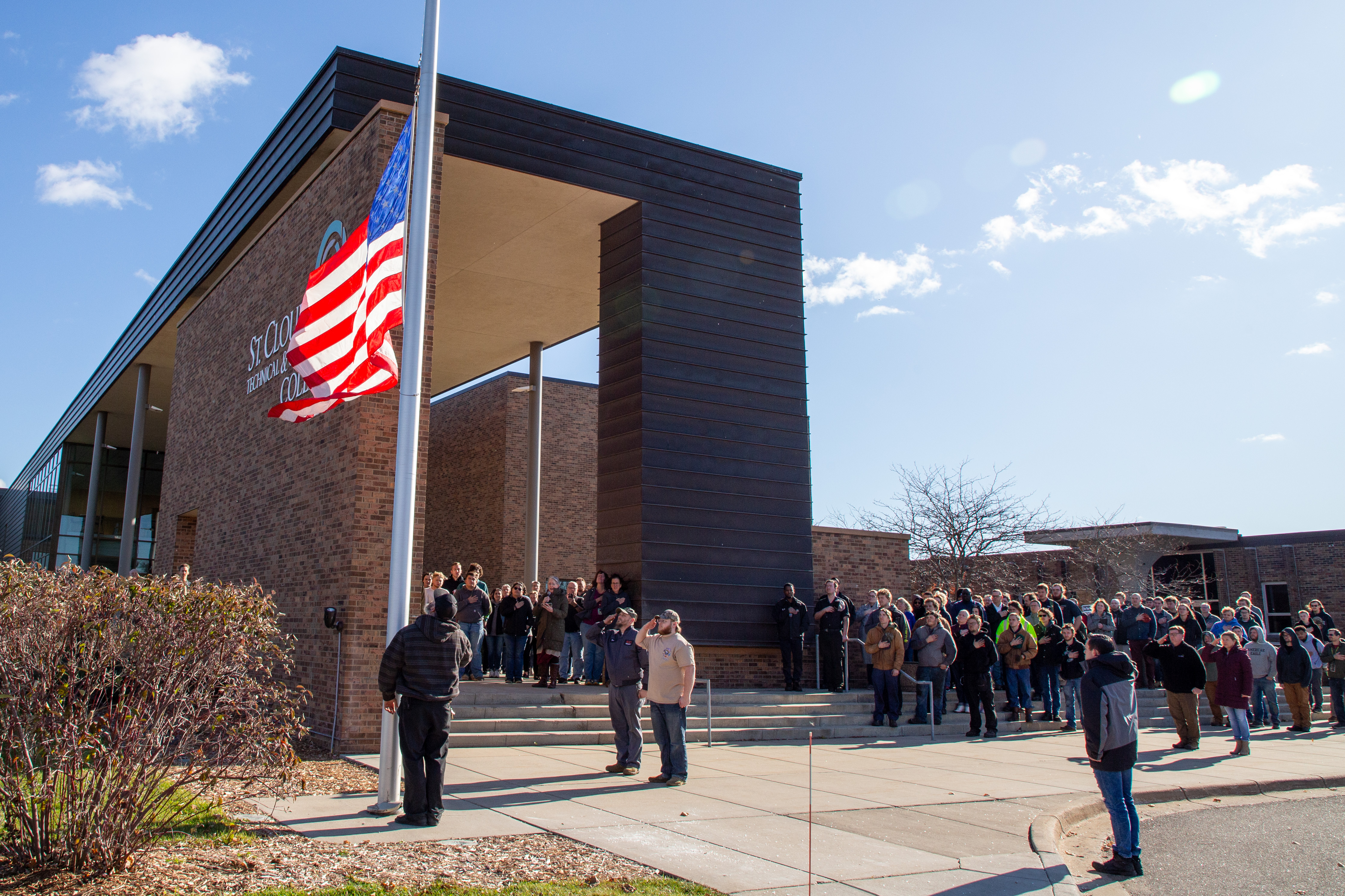 group of people looking up at flag at main entrance