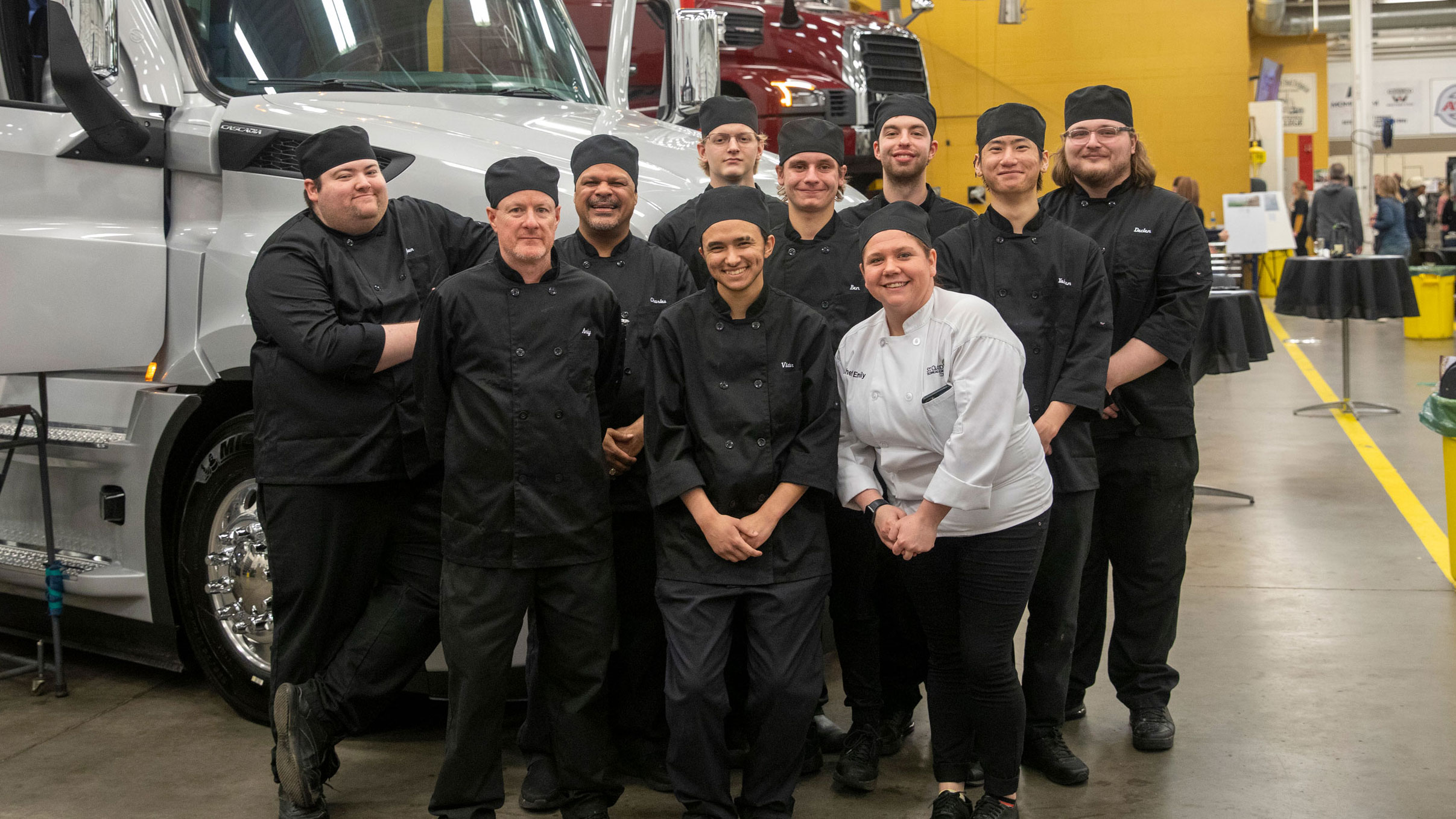 The culinary students in two rows in front of a semitruck